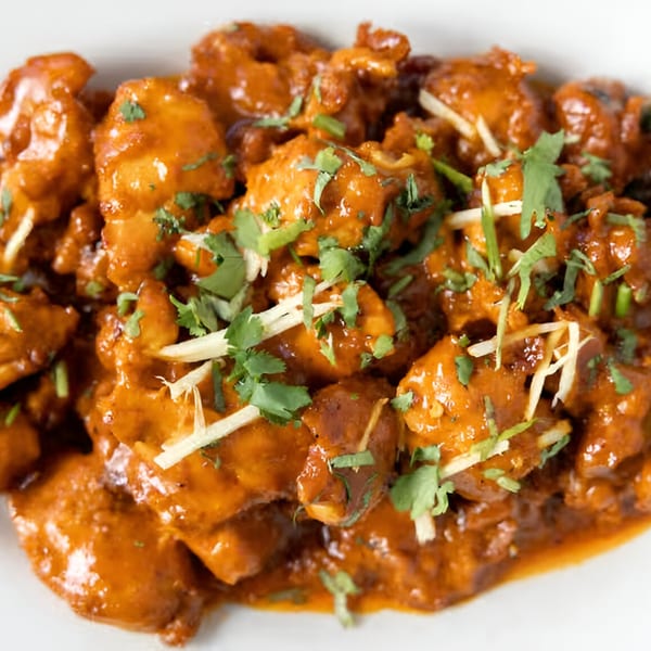 Close-up of Darbar Boston's chicken tikka masala, garnished with fresh cilantro and ginger slivers.