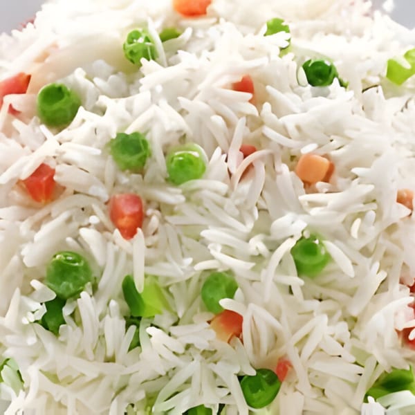Close-up of fluffy white basmati rice with vibrant green peas and diced orange carrots.